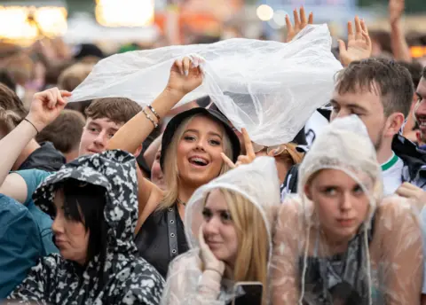 PA Media Music fans in plastic rain ponchos